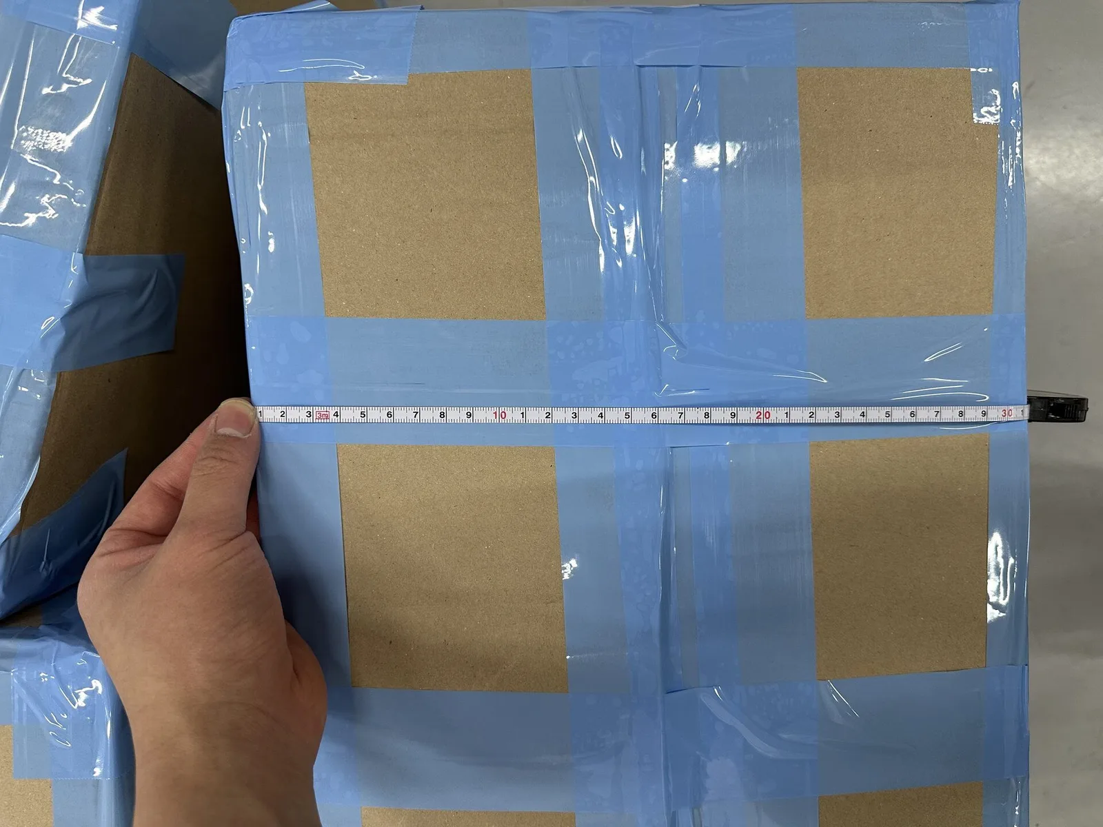 Measuring the width of a packed K-pop shipment carton